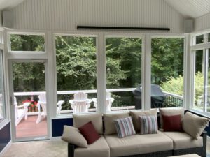 A bright sunroom with energy-efficient windows creates an inviting, comfortable space overlooking a peaceful deck.