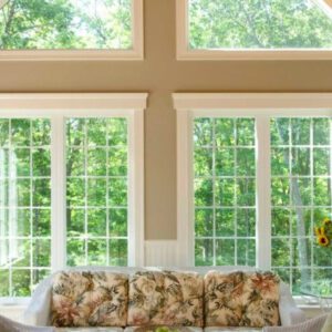 Sunlight spills over a floral couch, filling the room with warmth and a view of lush trees.