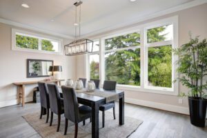 A sleek dining room centers around a black table, bathed in natural light with serene outdoor views.